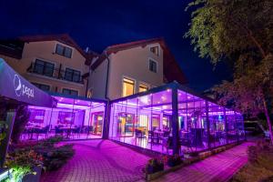 韦巴Hotel Sailor Łeba的建筑前方的玻璃建筑,有紫色的灯