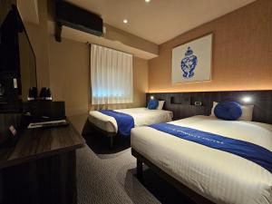 大阪Dynasty Hotel & Resort Osaka的酒店客房设有两张床和电视。
