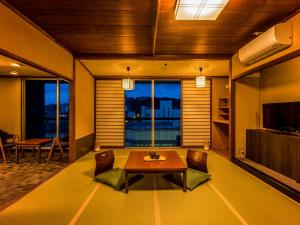 加贺Yukai Resort Saichoraku的客厅配有桌椅和电视。