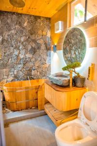 Làng CacChien's Lodge Du Gia的一间带木制浴缸和石墙的浴室