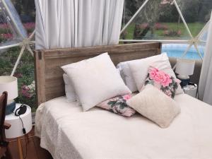 汉密尔顿Flowerhaven - glamping dome的床上铺有白色枕头和粉红色鲜花