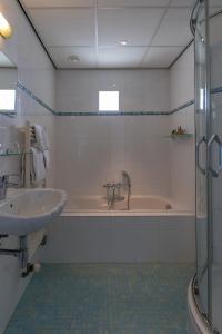 德科赫北海斯特兰酒店的浴室配有盥洗盆和浴缸。