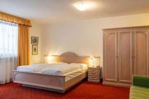圣坎迪朵思科芬霍夫酒店的一间卧室配有一张大床和一个梳妆台