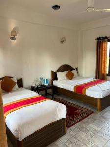 索拉哈Sauraha BnB的一间带两张床的卧室和一间带两张桌子的房间