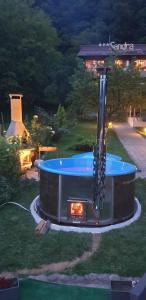 伯伊莱海尔库拉内Cazare Casa Sandra的庭院内的露天热水浴池,配有烧烤架