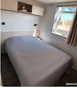 鲁西隆地区卡内Mobil home Canet Roussillon 4 étoiles le Mar Estang 8 pers的窗户客房内的一张白色床