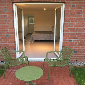 弗里克苏姆Nije Haven Bed & Breakfast的庭院里设有两把绿色椅子和一张桌子