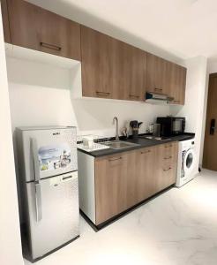 Al QurayyahClassy Studio in Masdar City的厨房配有木制橱柜和白色冰箱。