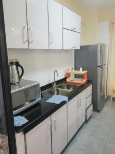 内罗毕JVhomes2bedroom-Ndemi gardens的厨房配有白色橱柜、水槽和冰箱。