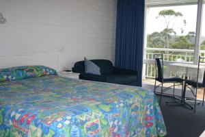 梅林布拉Kingfisher Motel (Adults only)的一间卧室配有一张床、一张桌子和一把椅子