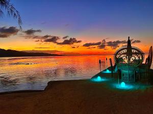 PatioEDEN Private Island TAHAA的日落时分在湖岸边的长凳