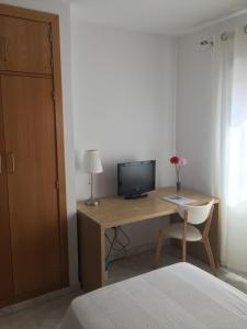 RocianaHostal Monteluna的一间卧室配有一张桌子、一台电视和一张床