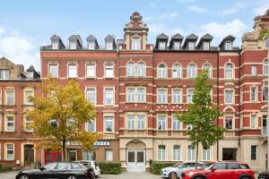 霍夫EasyApartments stilvoll zentral Balkon Hauptbahnhof NETFLIX 130m2的一座大型砖砌建筑,前面有汽车停放