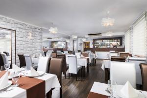 尼赖吉哈佐中央酒店的一间设有白色桌椅的餐厅和一间酒吧