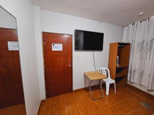 纳斯卡HOSTAL VEGA'S NAZCA的小房间设有一张桌子和一台墙上的电视