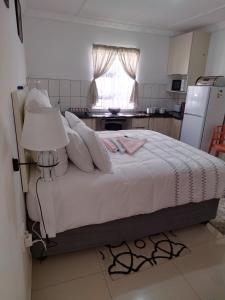 Ixopo4 Centenary Road Ixopo的一间卧室配有一张带白色床单的床和一台冰箱