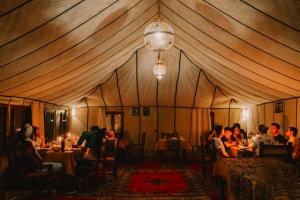 Adrouinedesert camp的一群人坐在帐篷里的桌子上