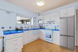 悉尼Bridge View 2 Bed Apartment at Kirribilli的厨房配有白色橱柜和蓝色台面