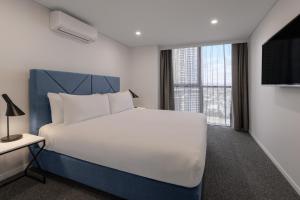 黄金海岸布罗德海滩美利通公寓式酒店的卧室设有白色的床和大窗户