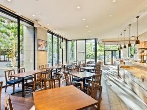 柏市三井花园饭店柏叶 / 千叶的餐厅设有木桌、椅子和窗户。