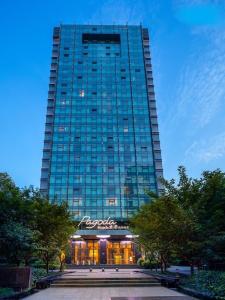 杭州杭州西湖武林Pagoda君亭设计酒店的一座高大的玻璃建筑,前面有一间商店