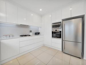 金德拜恩Alloura 2的厨房配有白色橱柜和不锈钢冰箱