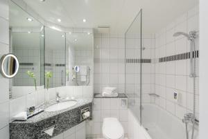 波鸿波鸿市美居酒店的白色的浴室设有水槽和淋浴。
