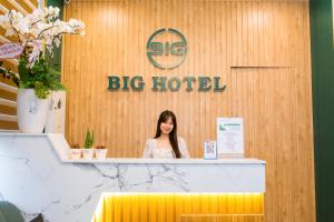 顺化BIG Hotel Huế的一位站在大酒店柜台后面的女人