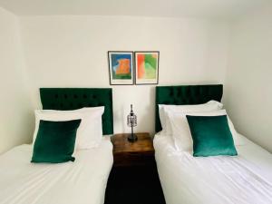 格洛斯特Penthouse - Contractors Professionals的两张带绿色和白色枕头的床