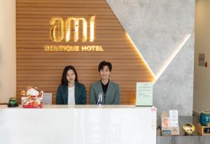 大叻Ami Boutique Hotels Đà Lạt的站在柜台后面的男人和女人