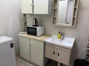 乌姆莱季Al-Olaya Apartment的一间带水槽和微波炉的小厨房