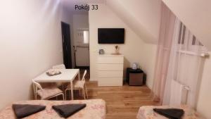 库瑞尼卡慕斯卡Pod Dębem的客房设有两张床、一张桌子和电视。