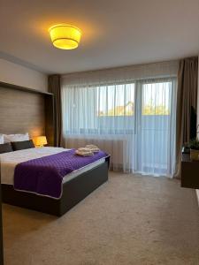 布拉索夫Luxury Glam Apartments & Studios near Coresi Mall的一间卧室配有一张大床和紫色棉被