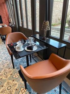 阿拉斯Maison Manotte d’Artois的一张桌子、两把椅子和一张桌子,桌子上放着杯子和咖啡