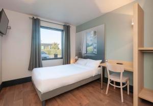 波城B&B HOTEL Pau Zénith的一间卧室配有一张床、一张桌子和一个窗户。