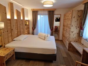 塞尔瓦迪加尔代纳山谷姆丽柯酒店的一间卧室设有一张床和木墙
