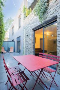 蒙彼利埃Le Beau séjour的露台上配有红色野餐桌和两把椅子
