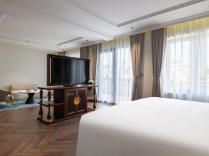 河内L'Signature Hotel & Spa的配有一张床和一台平面电视的酒店客房