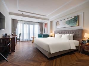 河内L'Signature Hotel & Spa的酒店客房设有一张白色大床和一张书桌