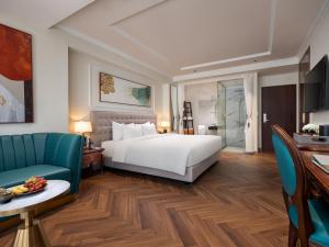 河内L'Signature Hotel & Spa的酒店客房带一张床、一张桌子和椅子