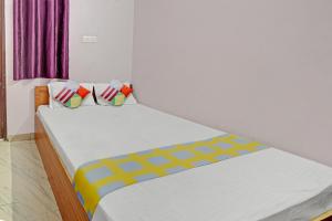 巴特那Super OYO Hotel Happy Inn的卧室配有一张带彩色枕头的大型白色床。