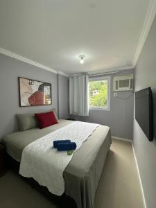里约热内卢Suites W-Riocentro的一间卧室配有一张带蓝色枕头的床