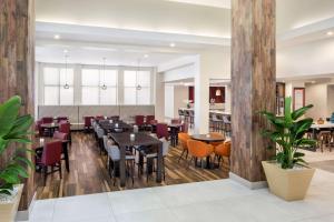 迈阿密迈阿密机场西希尔顿花园酒店的餐厅铺有木地板,配有桌椅