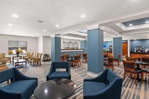 维洛海滩Comfort Suites Vero Beach I-95的大堂设有蓝色的桌椅和餐厅。