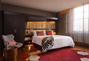 悉尼悉尼QT精品酒店的一间卧室配有一张大床和红色地毯。
