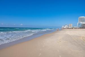 巴特亚姆Hi-Yam SeaView Apartments & Suites - יש ממ"ד的沙滩上的人在沙滩上和大海上散步