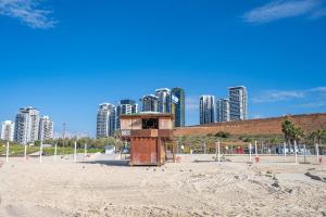 巴特亚姆Hi-Yam SeaView Apartments & Suites - יש ממ"ד的海滩上一座有高楼建筑的救生塔