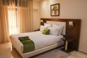马拉喀什Appart-hotel Marrakech Inn的卧室配有带绿色枕头的大型白色床