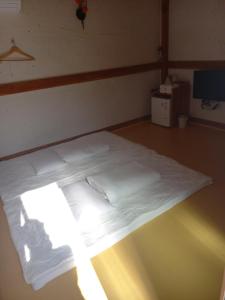 庆州Adam Guesthouse的一张位于白色床单和浅色客房内的床铺