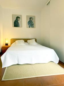 维拉诺瓦-德法马利Casa do Tanque的卧室配有一张白色床,墙上挂有两张照片